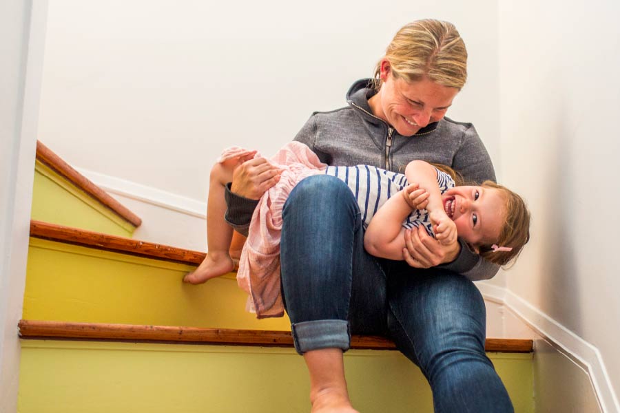Mother sat on stairs with her child in arms smiling