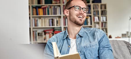 Man smiling while reading a book