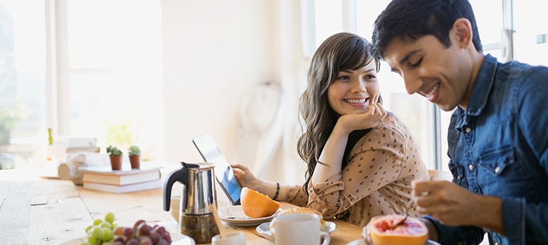 young couple sat at kitchen table eating breakfast