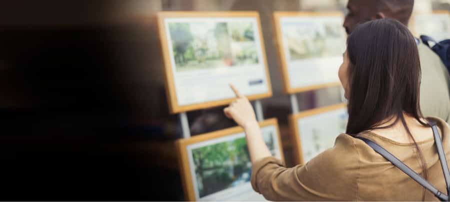 Lady looking at homes for sale in estate agent window