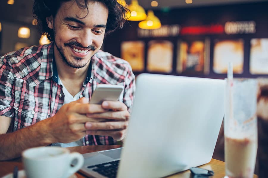 Man looking at phone in cafe smiling