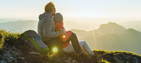 Couple sitting down outdoors on a hill/mountain