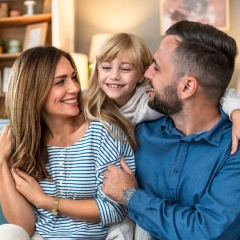 smiling girl with arms around her mother and father