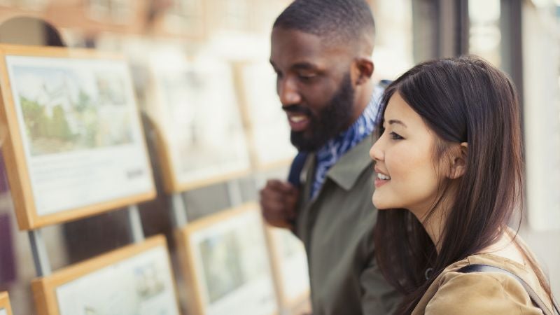 Man and woman smiling looking at real estate properties