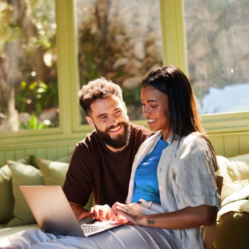 Smiling couple looking at laptop in a sunny room