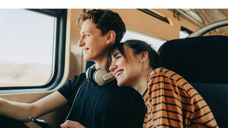Young couple smiling while looking out of train window.