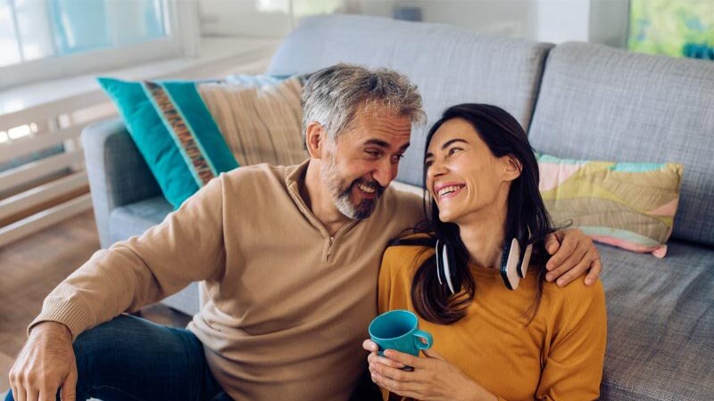 Couple sat on floor smiling at each other