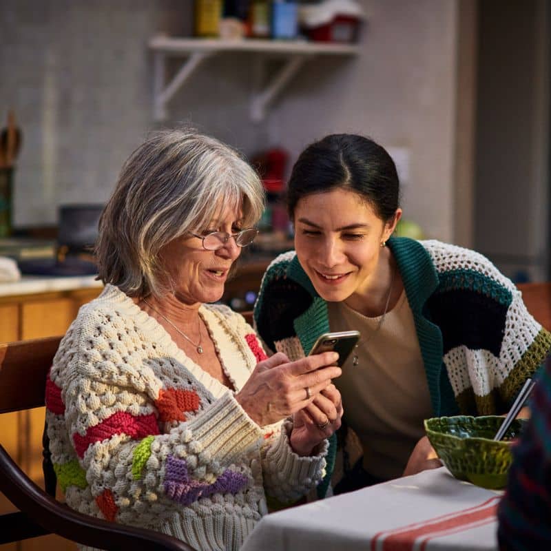 two women smiling looking at a mobile phone