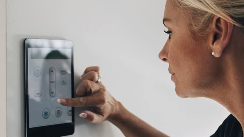 Woman using a thermostat app on a wall-mounted touch screen