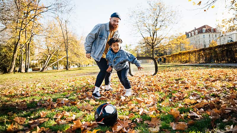 man and boy playing football in a park