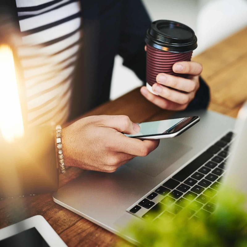 Person holding coffee and scrolling on their phone