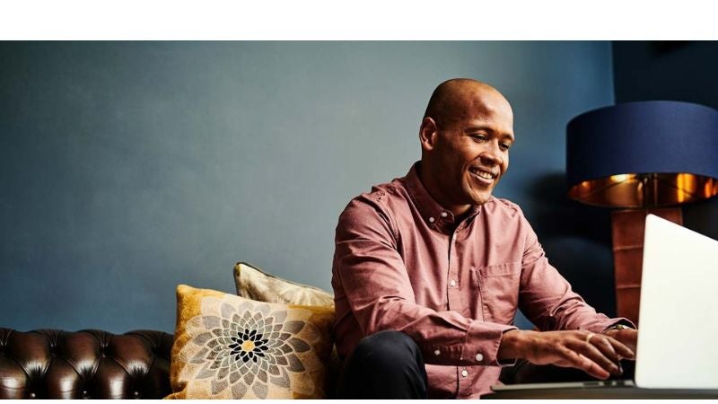 Man smiling while typing on laptop.