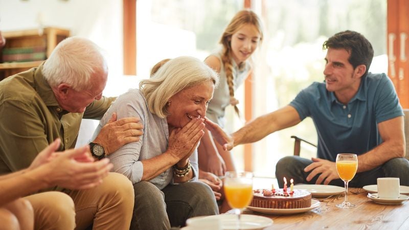 Family celebrating woman's birthday over cake.