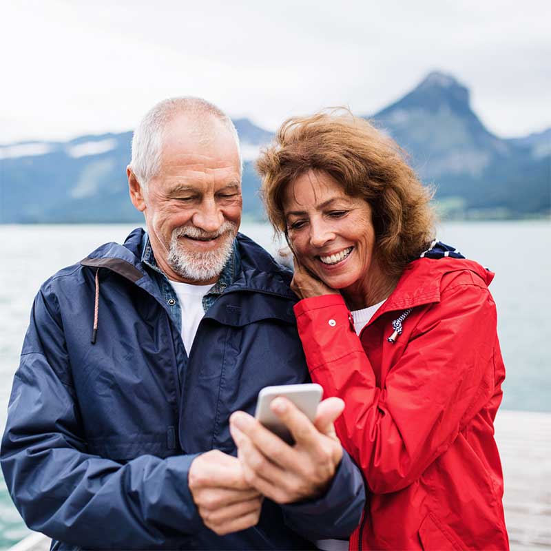 older couple stood outside smiling at phone
