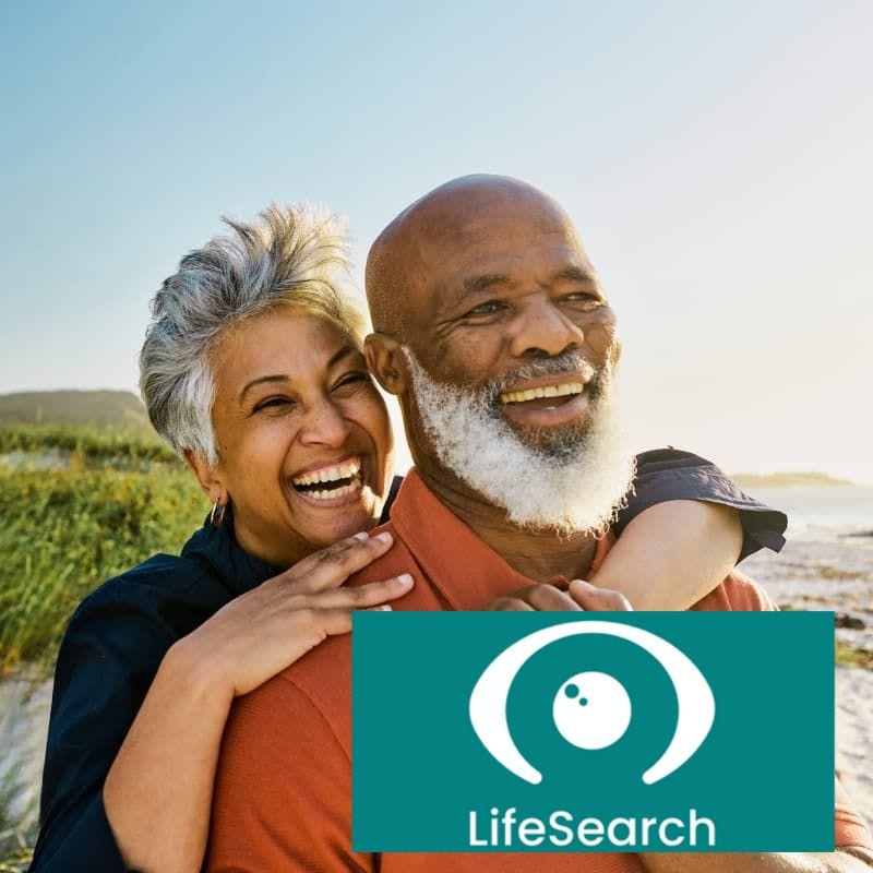 An older couple on a beach with the LifeSearch logo overlaid.